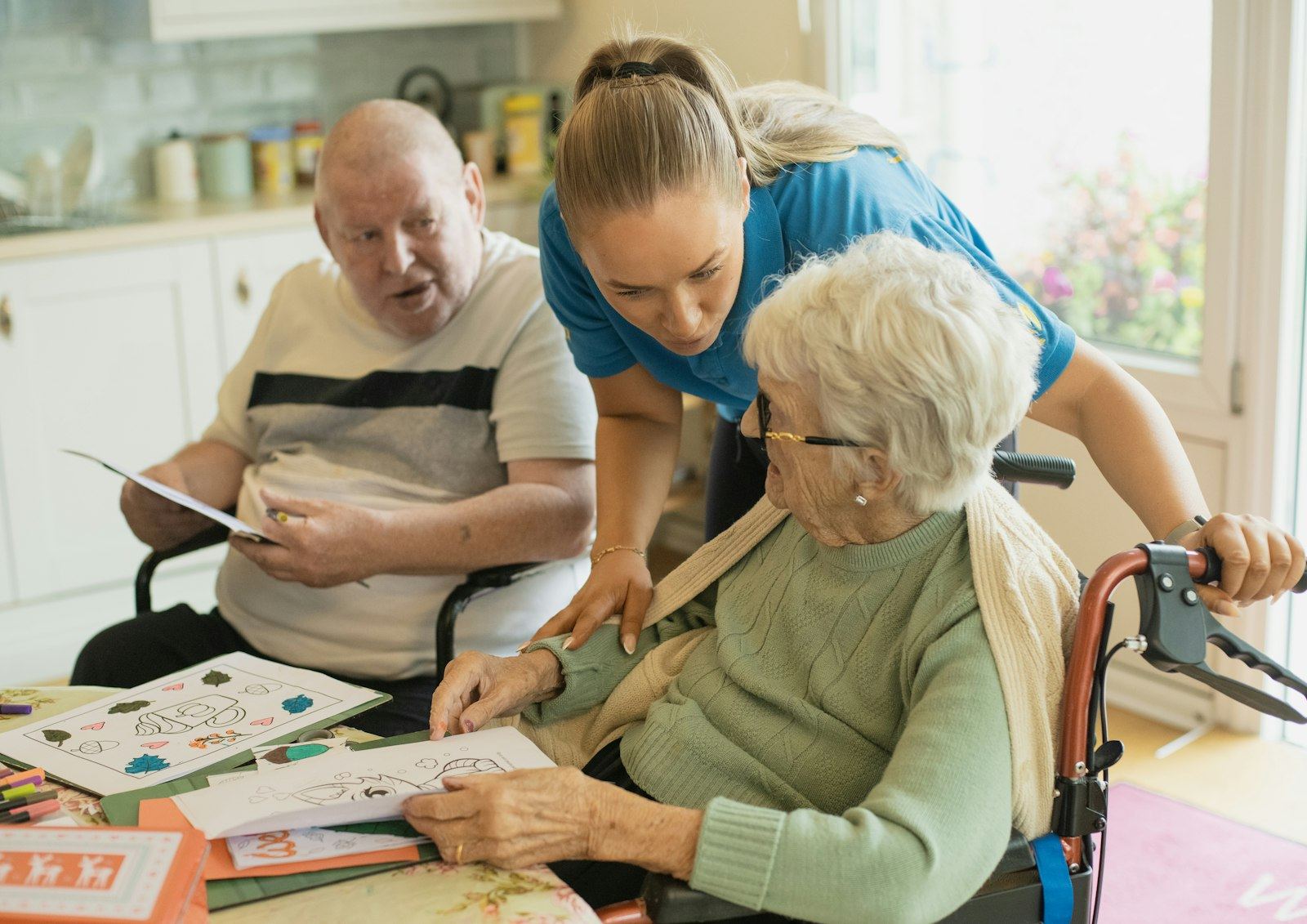 A caregiver helping an older couple at their kitchen table