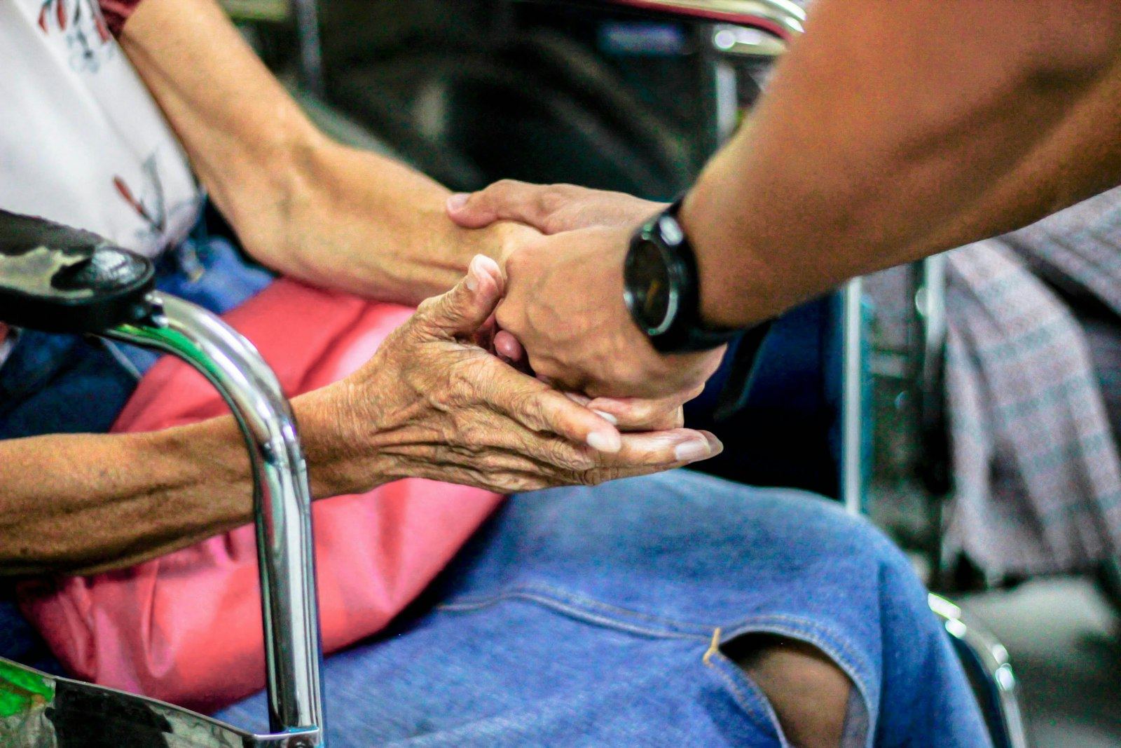 A caregiver holding an older person's hand